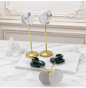 Detail of dark green resin ear mold on golden metal stand for jewelry display