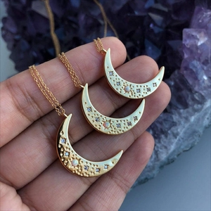Detail of three layered gold crescent moon necklaces with hammered texture and small opals