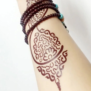 Waterproof henna tattoo sticker with reddish-brown lace pattern on arm with beaded bracelets