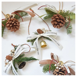 Detail of pine cones, evergreen branches, and bells with Just For You ribbons