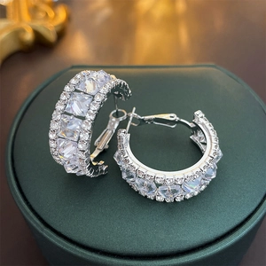 Macro shot of silver hoops with large square-cut cubic zirconia on green velvet box