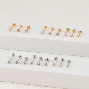 Detailed macro view of flat back threaded ear studs in gold and silver plating with zircon