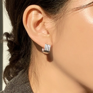 Detailed close-up of vertical striped 925 sterling silver geometric huggie earring on ear
