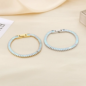 Detail of gold and silver steel bracelets featuring rectangular light blue zircons