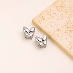 Detail view of butterfly shaped stainless steel earrings on a textured stone display