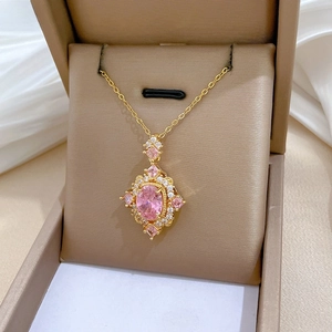 Detailed macro view of a gold-plated necklace with a pink rhumbic pendant and white crystals