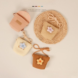 Flat lay detail showing woven straw crossbody bags for kids in four pastel colors with cloth flowers