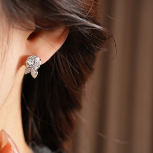 Primo piano di un orecchino a fiore in zircone d'argento sul lobo di una donna