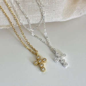 Close-up of gold and silver cross necklaces with sparkling cubic zirconia on fine chains