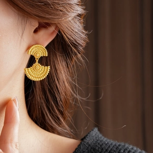 Gros plan de boucles d'oreilles vintage dorées en forme d'éventail perlé sur modèle
