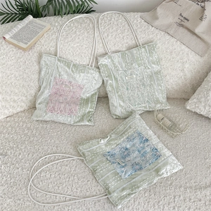 Detail of lace-trimmed green velvet tote bag with colorful floral patch pockets