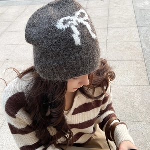 Detail of soft charcoal grey knitted beanie with fuzzy white bow pattern for women