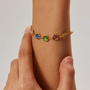 Détail d'un bracelet plaqué or 18 carats avec pierres œil-de-chat colorées portées au poignet