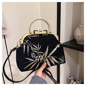 Detail of Chinese style embroidery featuring golden leaves on a black silk handbag