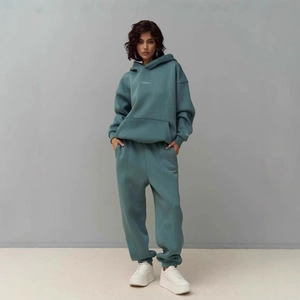 Detail of teal blue hooded tracksuit featuring drop shoulders and elastic cuffs