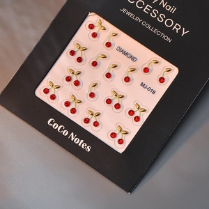 Detailed view of red cherry nail jewelry with gold leaves on MJ-018 display card