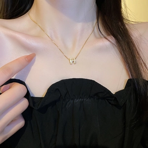 Close-up of a gold-plated H-shaped necklace featuring a high-quality mother of pearl inlay