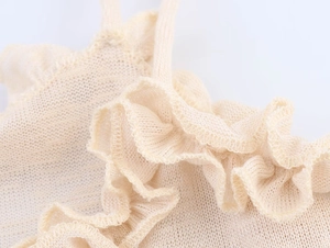 Detailed view of beige knit tank top featuring delicate ruffle hem and fine textures