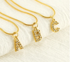 Macro view of gold plated A B C letter pendants with crystals on a sleek snake chain