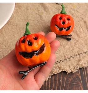 Close-up of bright orange pumpkin hair clips with resin faces and silver metal base