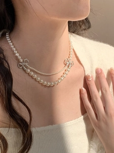 Détail d'un élégant collier de perles double couche avec nœud en strass sur le cou
