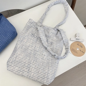 Detail of blue and white checkered canvas tote bag with ruffled strap and Solaika embroidery