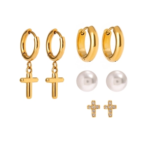 Set di quattro orecchini in acciaio dorato con croci, perle e strass su sfondo bianco