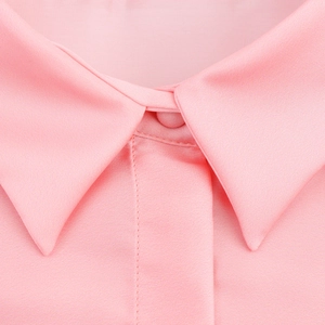 Gros plan du col de chemise en satin rose avec fermeture délicate à bouton et boucle