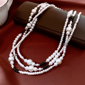 Détail d'un collier de perles multicouche avec perles noires sur cuir et soie rouge