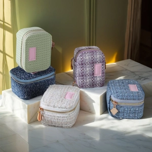 Nahaufnahme von Mini-Schmuckkästchen aus Tweed in vielen Farben auf weißem Marmor