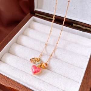 Macro view of 18k gold plated heart pendant with pink enamel and colorful bead accents