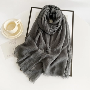 Detailed texture of dark grey linen scarf with raw edges and minimalist coffee scene