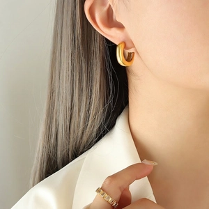 Pendientes de aro en C dorados pulidos y anillo de circón baguette usados por una modelo
