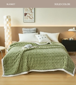 Detail of sage green bubble textured blanket with soft plush fabric and white piping edge