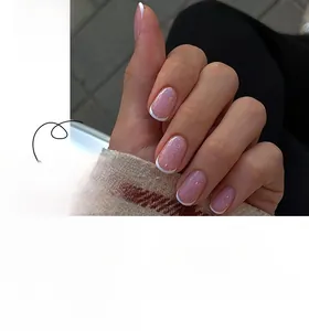 Macro view of French short round press-on nails with white tips and pearl pink base finish