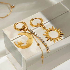 Gold celestial earrings set with sun moon star charms and rhinestone tassels on stand