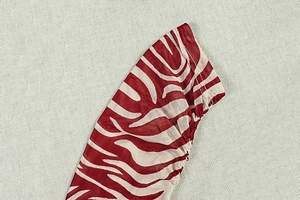 Dettaglio del tessuto a rete con stampa zebra rossa e cuciture overlock di alta qualità