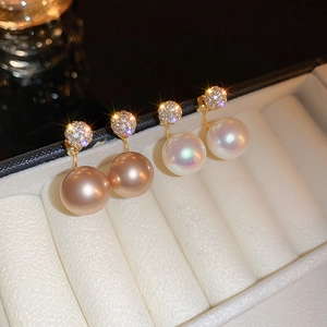 Close-up of geometric gold-plated earrings with champagne and white pearls and zircon