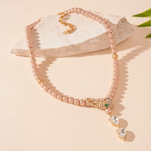 Detail of crystal snake head and teardrop pendants on champagne pearl necklace