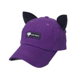 Détail d'une casquette violette avec oreilles de chat noires et étiquette Hand Made