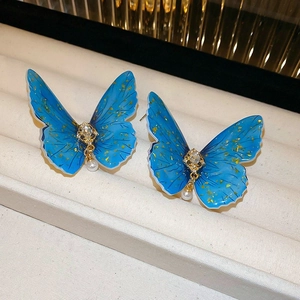 Gros plan de boucles d'oreilles papillon en tulle bleu avec paillettes d'or et perle