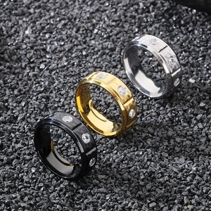Close-up of 8mm textured titanium steel rings in black, gold, and silver on stones