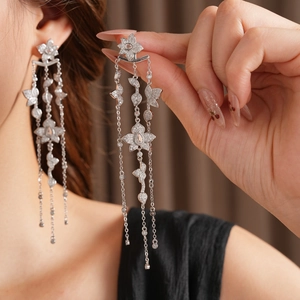 Detail of silver long tassel flower earrings with sparkling crystals worn by a model