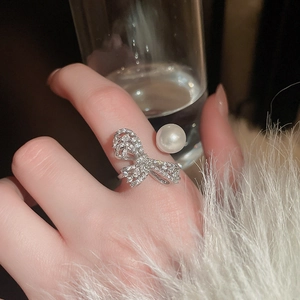 Detailed view of silver bow-tie ring with zircon accents and a single white pearl