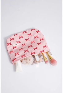 Pink bow cotton makeup bag with cosmetics inside, featuring golden brushes and zipper detail
