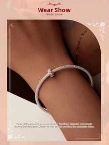 Mesh silver bracelet featuring a rose gold pave charm on a model's wrist