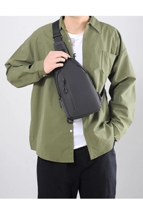On-model view of a dark grey crossbody chest bag with matte texture and zippers