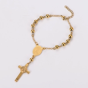 Detail of gold beaded rosary bracelet featuring Virgin Mary medal and cross pendant