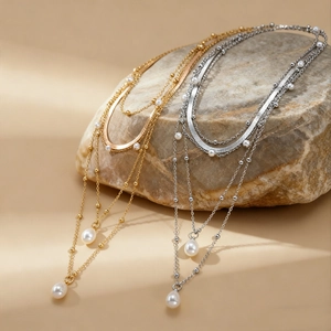 Detailed view of layered necklaces in gold and silver finish with teardrop pearls