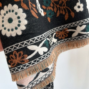Detail of floral cashmere-feel scarf featuring white flowers and brown fringe tassels